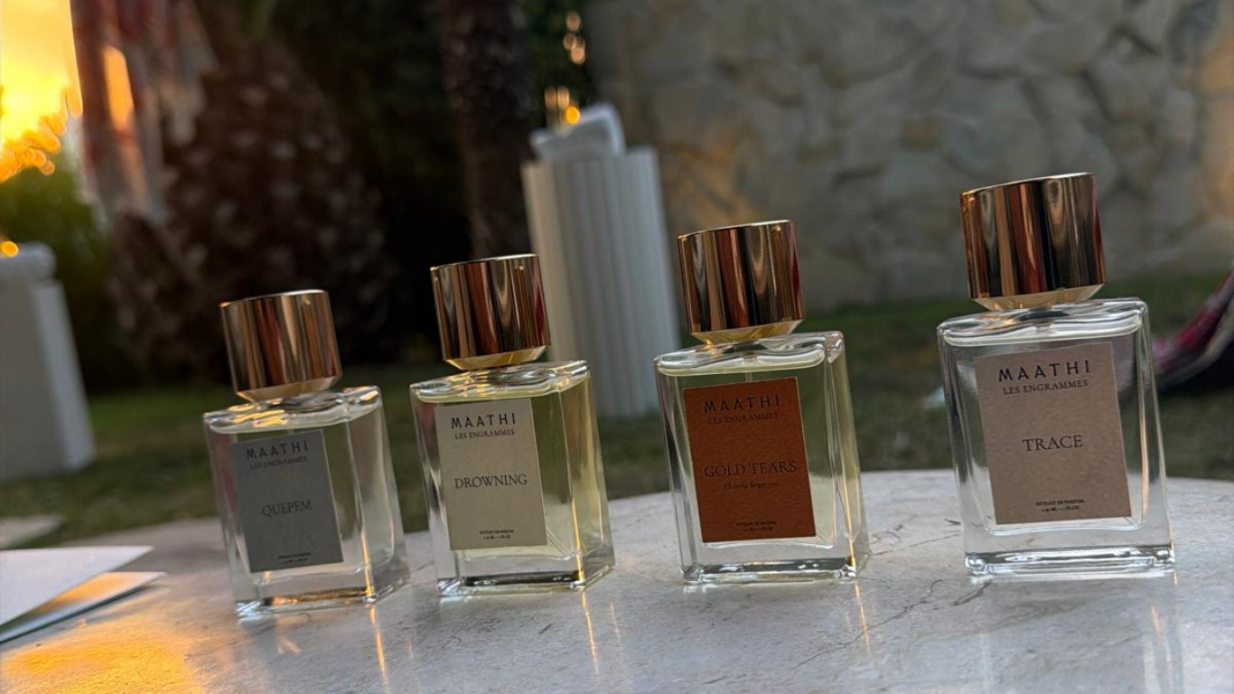 MAATHI Les Engrammes fragrance collection displayed outdoors in Saint-Tropez, featuring four extrait de parfum bottles: Quepem, Drowning, Gold Tears and Trace.