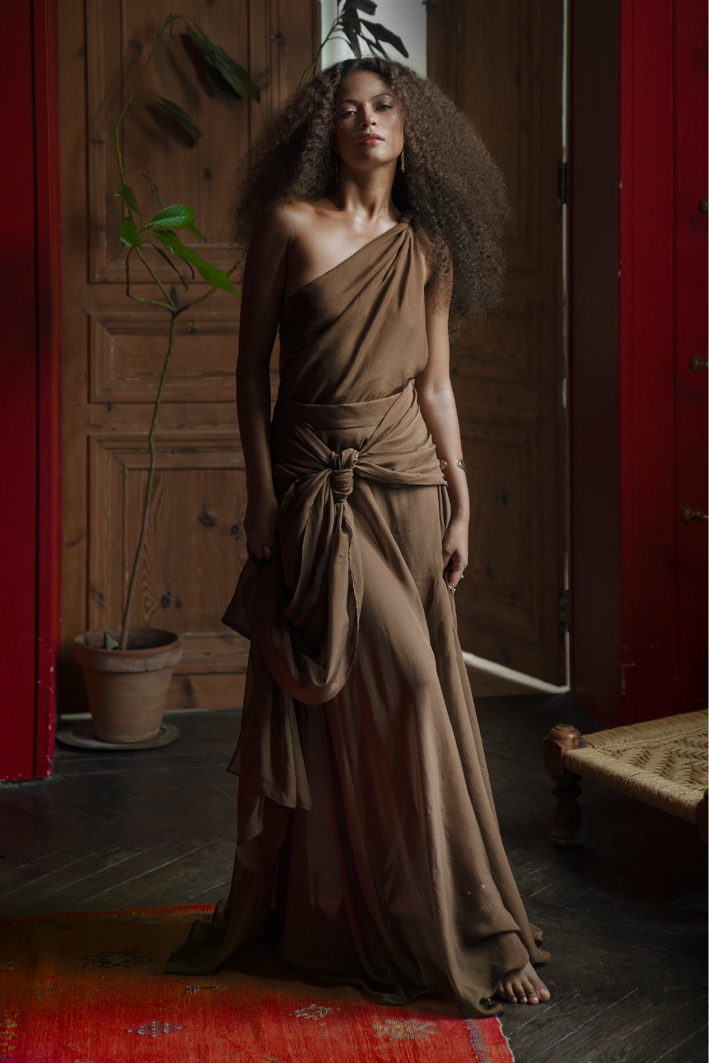 Model wearing the Drift Silk Skirt and Ebb Silk Knot Top in rich brown silk, photographed indoors with dramatic draped styling for maathi paris