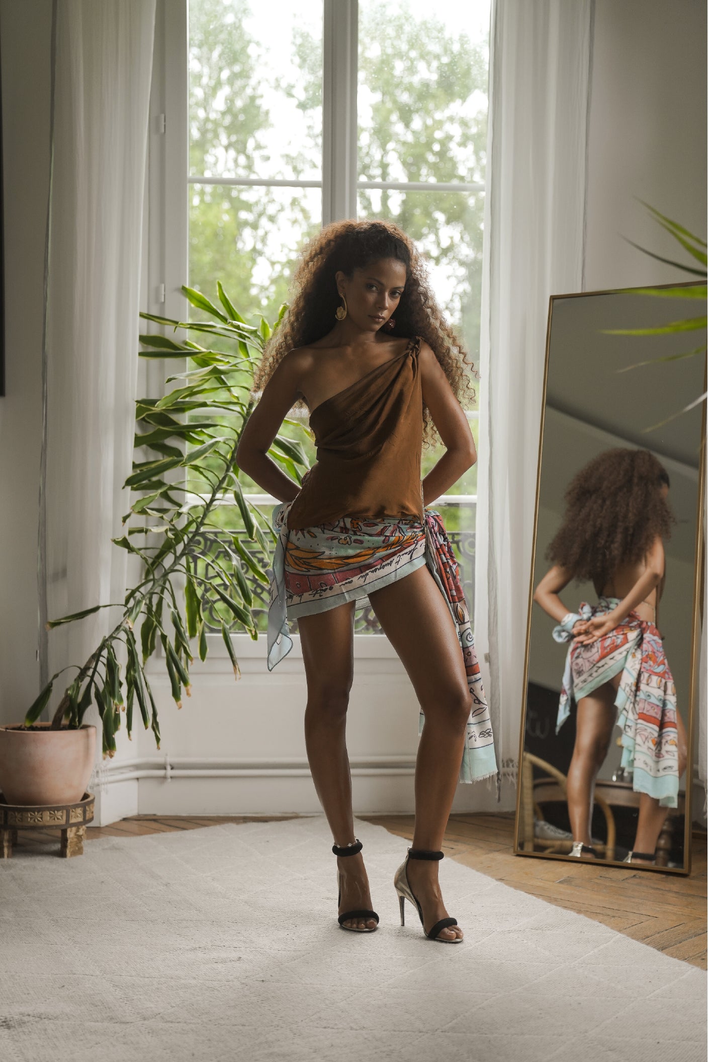 Woman wearing the Shore cotton sarong in a modern interior, styled as a wrap skirt, luxury resortwear by Maathi Paris.