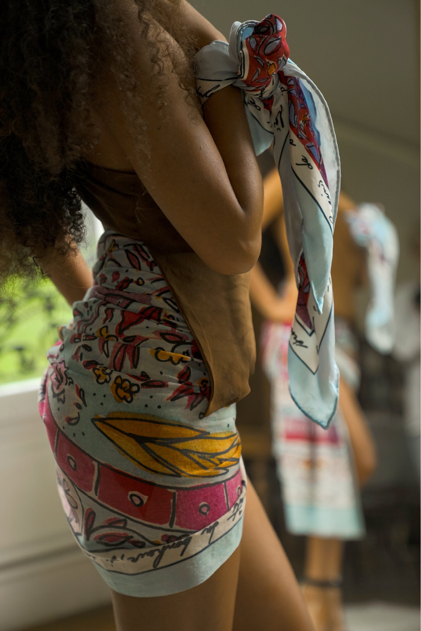 Close-up of the Shore cotton sarong being tied around the hips, showcasing the colourful Fleur de Cajou artist print.