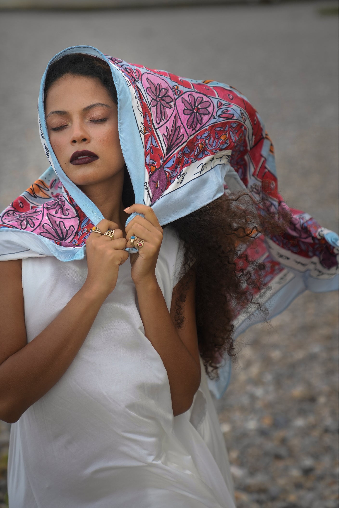 Portrait of a model wearing the Tide Silk Scarf draped over her head with the Moonwake Dress in flowing white silk
